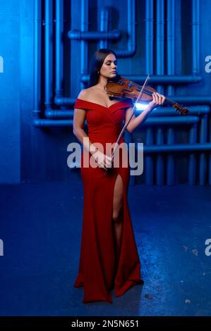 Young pretty woman playing violin solo over loft interior background Stock Photo