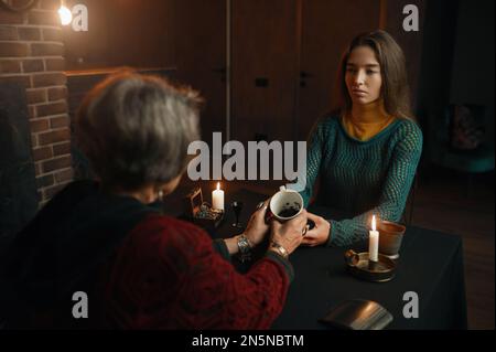 Young woman visiting gypsy witch for divination on coffee grounds Stock Photo