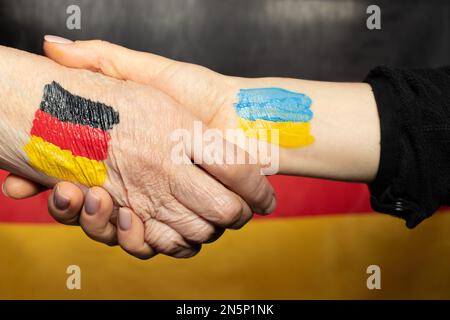 Two hands one with a drawn flag of Germany and the second with a drawn flag of Ukraine handshake, union and unity Stock Photo