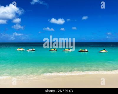 personal watercraft lined-up in the water, just off the beach, Eagle Beach, Aruba Stock Photo