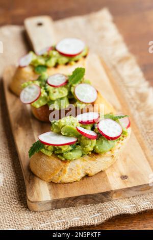 Bruschetta with Fava Beans, Radishes and Mint on a cutting board Stock Photo