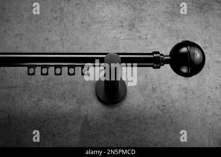 Classic black plastic eaves with a round end, on a gray concrete wall Stock Photo