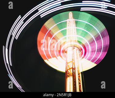 Multicolored Star Flyer tall Carousel rotating on long chains in an amusement park. Entertainment and leisure activities concept. Stock Photo