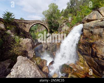 Ponte da Misarela or Bridge of Mizarela in Montalegre, Portugal with a big waterfall next to it during a sunny day. Rural travel and holidays. Stock Photo
