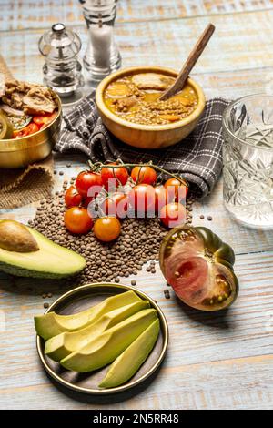 still life with tomatoes, pieces of tomatoes, lentils, a glass of water, kitchen towels, lentil stew and a plate of salad with tuna and tomatoes on a Stock Photo