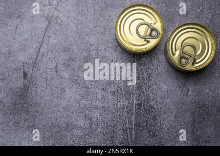 Two small circular tin cans closed with easy-open rings on gray surface Stock Photo