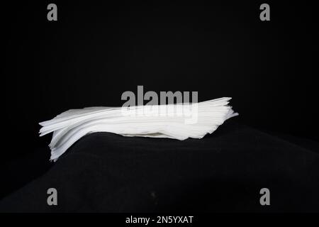 pile of white paper napkins isolated on a black background seen edge on Stock Photo