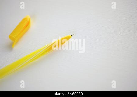 Yellow ball pen and cap close-up on a white table. Stock Photo