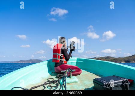 Rear view of an equipped marine biologist working while talking photo on a boat Stock Photo