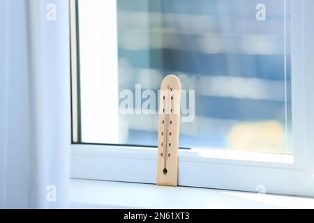 Wooden weather thermometer on window sill indoors Stock Photo