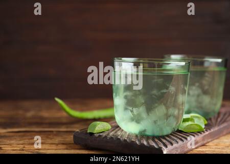 Fresh aloe drink in glasses on wooden table, closeup. Space for text Stock Photo