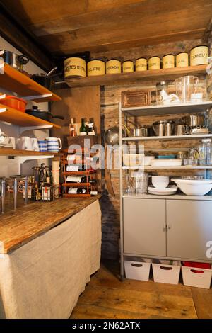 Pantry stocked with dishes, pots , pans and wine bottles inside old 1752 home. Stock Photo