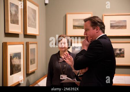 British Prime Minister David Cameron, right, is shown the newly discovered previously unknown oil sketch painting by John Constable entitled 'Landscape with a Kiln' from 1821 or 1822 by Head Painting Conservator Nicola Costaras, below left, as an additional part of his visit to the 'Masterpieces of Chinese Painting: 700-1900' at the Victoria & Albert Museum in London, Thursday, Nov. 28, 2013. The museum said it was discovered when conservators attempted to remove the lining on the back of 'Branch Hill Pond: Hampstead', another work by the English romantic painter known for his landscapes, whil