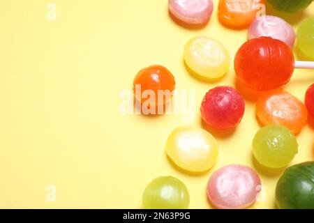 Many different hard candies on yellow background, closeup. Space for text Stock Photo