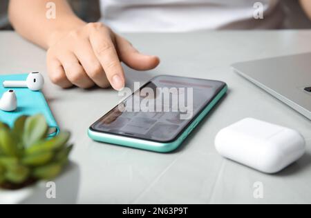 MYKOLAIV, UKRAINE - JULY 10, 2020: Woman using with Pinterest app on Iphone 11 at table, closeup Stock Photo