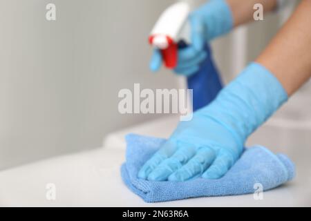 Woman cleaning toilet bowl with rag and detergent in Stock Photo