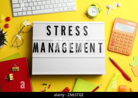 Flat lay composition of lightbox with phrase Stress Management on yellow  background Stock Photo