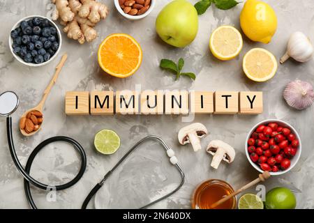 Cubes with word Immunity, stethoscope and fresh products on grey table, flat lay Stock Photo