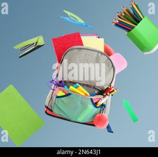 Backpack surrounded by flying school stationery on color background Stock Photo