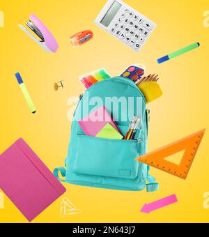 Backpack surrounded by flying school stationery on yellow background Stock Photo