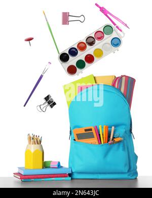 School stationery flying over backpack on white background Stock Photo