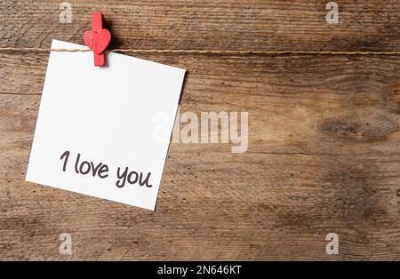 Card with words I Love You hanging on wooden background. Space for text Stock Photo