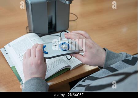 A visually impaired man uses a scanning and reading machine. Stock Photo