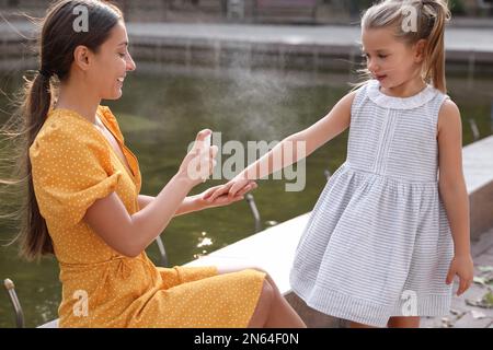 Mother applying insect repellent onto girl's hand outdoors Stock Photo