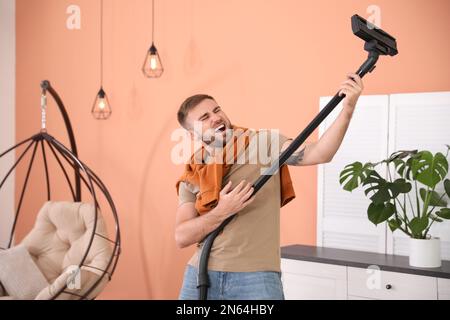 Young man having fun while vacuuming at home Stock Photo