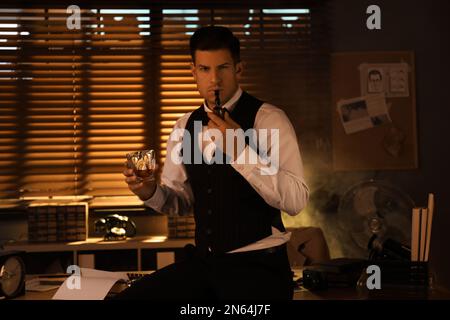 Old fashioned detective with drink and smoking pipe in office Stock Photo