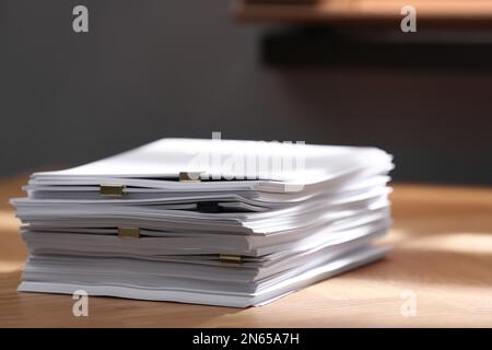 Stack of blank paper with binder clips on wooden table indoors Stock Photo