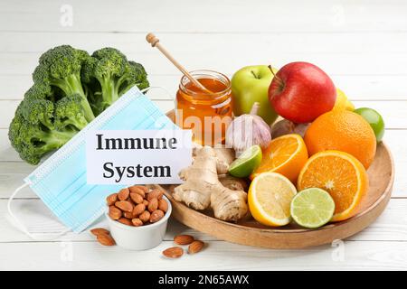 Card with phrase Immune System, medical mask and fresh products on white wooden table Stock Photo