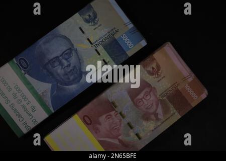stacks of IDR 100,000 and IDR 50,000 rupiah banknotes on black background Stock Photo