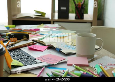 Laptop, notes and office stationery in mess on desk. Overwhelmed with work Stock Photo