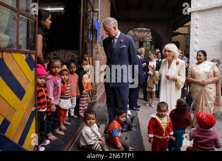 Britain's Prince Charles looks at children as his wife Camilla, the Duchess of Cornwall, speaks with a school official at Katha Lab School, a school for underprivileged children, in New Delhi, India, Friday, Nov. 8, 2013. Charles and Camilla are on a nine-day visit to India. (AP Photo/Saurabh Das)