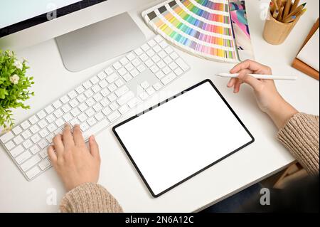 Top view of a professional female graphic designer or freelance editor working at her modern desk, using laptop and digital tablet. tablet white scree Stock Photo