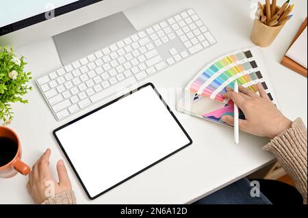 Top view of a female graphic designer working at her desk, choosing her product template color from color palette, using digital tablet. tablet white Stock Photo