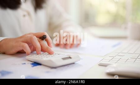 Close-up image of a professional Asian female accountant or financial analyst using calculator, working at her desk. Stock Photo