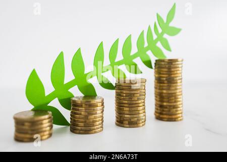 green economy investment and profit opportunities conceptual image, stacks of growing coins with green leaves  on them Stock Photo