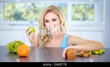Right choice - Eat well and stay healthy. Pretty young woman choosing a healthy apple over junk food. Stock Photo