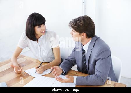 Working out the problems in the project - Business Strategy. Two young executives brainstorming at the office together. Stock Photo