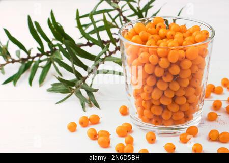 Sea buckthorn. Fresh ripe berries in a glass with leaves on a branch isolated on white background. concept of healthy drinks and herbs, healthy food Stock Photo