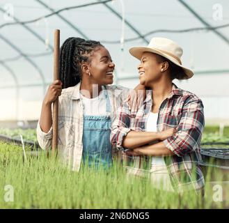 Happy farmers laughing and talking. Cheerful farmers working together in a greenhouse. African american colleagues working on a farm. Farmers Stock Photo