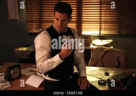 Old fashioned detective with drink in office Stock Photo