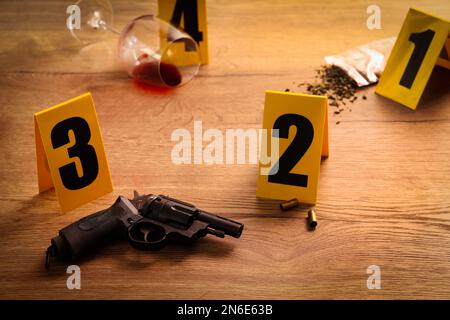 Crime scene markers, gun and shell casings on wooden table Stock Photo