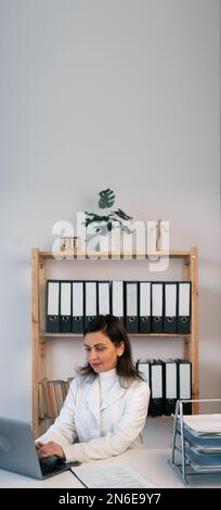 Female doctor using a laptop to record patient information at the hospital. health care and prevention concept. Copy space. Vertical banner Stock Photo