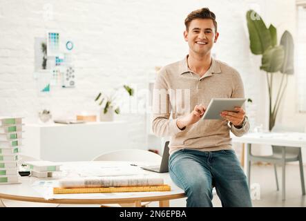 Portrait of a businessman using a digital tablet. Young architect using a wireless device to scroll online. Caucasian designer working on a digital Stock Photo
