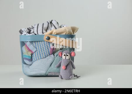 Laundry basket with different children's clothes and toy on light background. Space for text Stock Photo