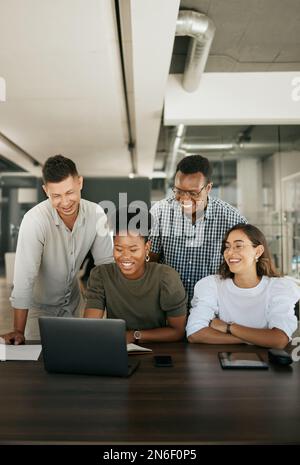 Diverse employees gathered in office having fun watching funny video, discussing new ideas, brainstorming using laptop enjoying break in workday Stock Photo