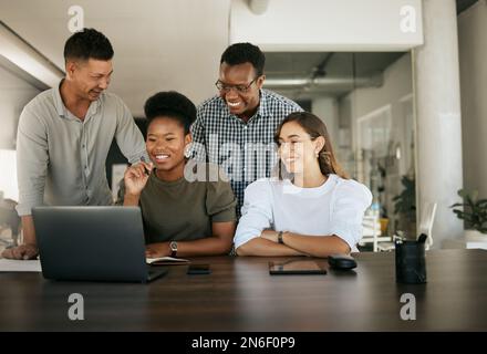 Diverse employees gathered in office having fun watching funny video, discussing new ideas, brainstorming using laptop enjoying break in workday Stock Photo